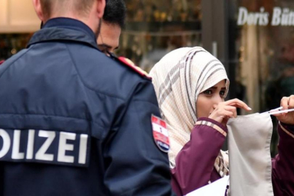 Un policía ordena a una mujer musulmana que se retire el velo en Austria.-AFP