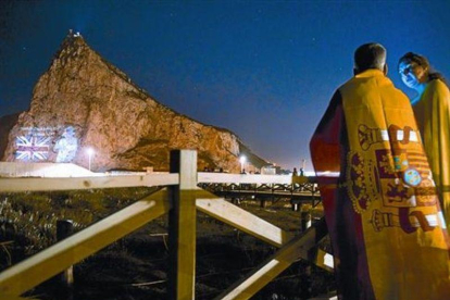 Una pareja mira desde la Línea de la Concepción la proyección de la imagen de Isabel II en el Peñón, en junio del 2012, cuando las autoridades de Gibraltar celebraron el 60º aniversario del ascenso al trono de la reina.-AFP / MARCOS MORENO