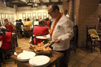 José María Ruiz trincha un cochinillo con un plato en una de las salas de su restaurante segoviano.-L.P.