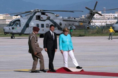 Renzi, Merkel y un oficial tratan de ajustar la alfombra roja en el aeropuerto de Nápoles, antes de desplazarse a Ventotene.-AFP / MARIO LAPORTA