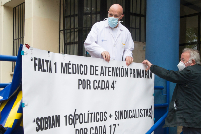 El doctor Juan José Jiménez coloca una pancarta reivindicativa junto al centro de salud. ISRAEL L. MURILLO