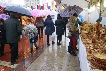 Buena parte de los comerciantes mantuvieron los puestos abiertos pese a la lluvia mientras que los compradores se refugiaban bajo los toldos o con paraguas.-R. OCHOA