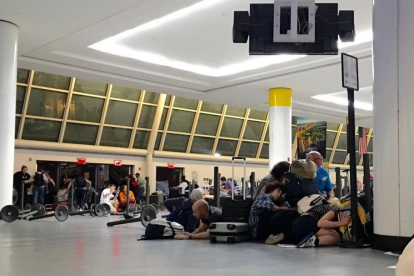 Pasajeros del aeropuerto JFK de Nueva York se protegen mientras la policía busca a un presunto tirador, la pasada madrugada.-AFP