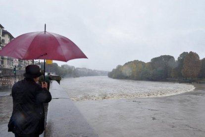 Varias personas observan la crecida del río Po durante unas fuertes lluvias en Turín. Cerca de once regiones italianas se encuentran en estado de emergencia debido a las lluvias y tormentas de los últimos días.-EPA/ANSA