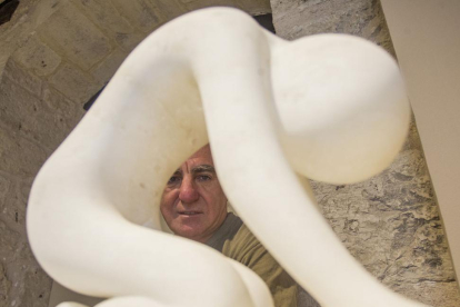 Julio Carazo se asoma por el aire que deja una escultura de alabastro titulada ‘De rodillas’.-Santi Otero