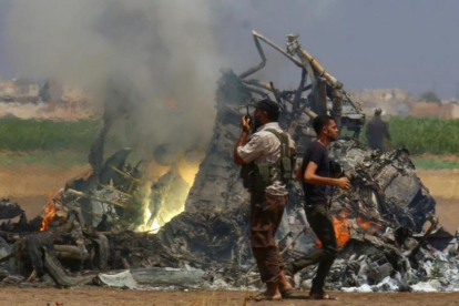 Un grupo de hombres inspecciona los restos del helicóptero ruso que los rebeldes sirios han derribado este lunes en la provincia de Idleb-REUTERS / AMMAR ABDULLAH