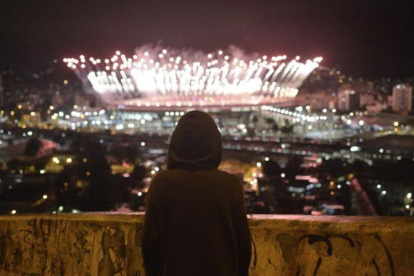 Un niño observa desde el Morro da Mangueira los fuegos artificiales de Maracaná durante la ceremonia de clausura de los Juegos, este domingo.-EFE / FABIO TEIXEIRA
