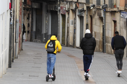 Tres jóvenes en patinete eléctrico por una céntrica calle de Burgos. RAÚL G. OCHOA