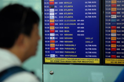 Un viajero consulta la programación de vuelos en el aeropuerto de Barcelona.-DANNY CAMINAL