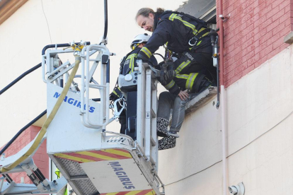 Uno de los bomberos accede a la ventana mientras otro conversa con el hombre.-ISRAEL L. MURILLO
