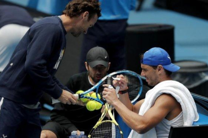 Nadal pone cinta en su raqueta ante la presencia de su entrenador, Carlos Moya.-