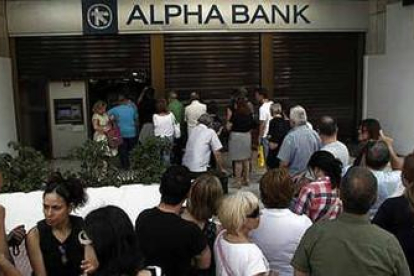 Decenas de personas hacen cola para sacar dinero de un banco en Atenas.-ALEXANDROS VLACHOS / EFE
