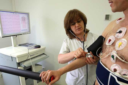 Una enfermera toma la tensión a un paciente que se somete a un electrocardiograma.-ICAL