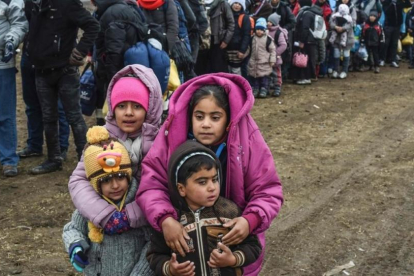 Unos niños sirios esperan junto a otros refugiados para cruzar la frontera entre Macedonia y Serbia.-/ AFP / ARMEND NIMANI