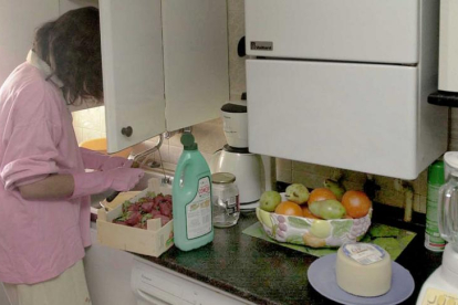 Una chica limpia una caja de fresas en su casa.-ISRAEL L. MURILLO