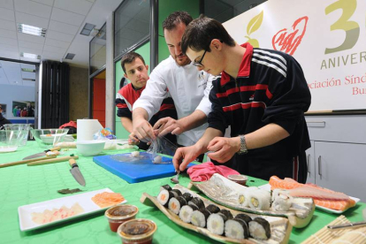 Saúl Gómez enseña a dos de los jóvenes que acudieron a la demostración a elaborar uno de los platos más típicos de la cocina japonesa, el sushi.-ISRAEL L. MURILLO