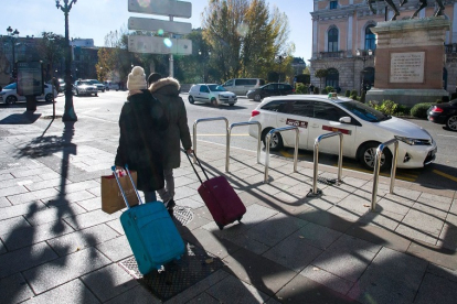 Una pareja de turistas camina por la plaza de Mío Cid, en Burgos, con sus maletas. TOMÁS ALONSO