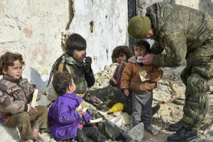 Un soldado ruso atiende a unos niños sirios en Aleppo, Siria.-