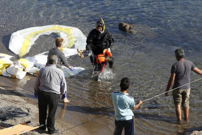 Un guardacostas griego saca del agua el cadáver de un niño refugiado en la costa griega de Lesbos.-REUTERS