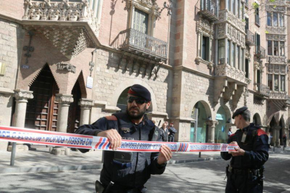 Dos agentes de los Mossos acordonan la zona mientras la Guardia Civil inspecciona la sede del Diplocat, durante un registro el pasado 12 de abril.-ALAN RUIZ TEROL (ACN)