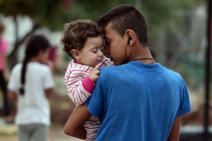 Un chico sostiene en brazos a su hermano pequeño en el campo de refugiados de Kara Tepe, donde algunos fueron trasladados tras un incendio en el de Moria, en Lesbos (Grecia), el 21 de septiembre.-AFP / LOUISA GOULIAMAKI