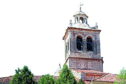 La torre de la iglesia de Santa Cruz surge entre el arbolado.-LUMIAGO