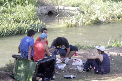 Un grupo de jóvenes hace botellón en la orilla del río.-ISRAEL L. MURILLO