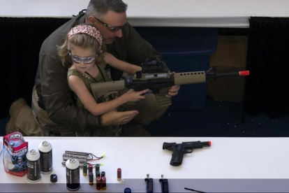 Un hombre muestra a una niña cómo coger una escopeta de aire comprimido durante el NRA Youth Day, en la reunión anual de la NRA, en Houston, en el 2013.-/ REUTERS / ADREES LATIF