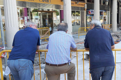 Tres hombres mayores conversan mientras observan una obra apoyados en una valla metálica.-ISRAEL L. MURILLO