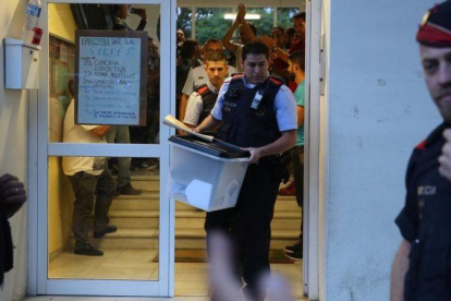 Un mosso se lleva una urna de un colegio durante el referéndum del 1-O.-RICARD CUGAT