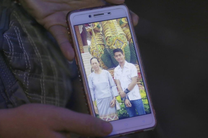 La tia de Ekapol Chanthawong muestra una foto en el móvil del entrenador en la que aparace junto a su abuela.-AP