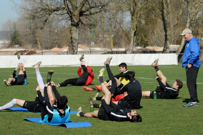 Un grupo de jugadores del Burgos CF realizan estiramientos ante la atenta mirada de Mandiola-I. L. Murillo