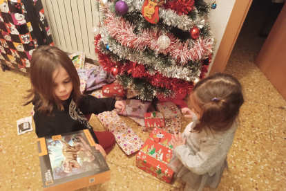 Dos hermanos abren sus regalos junto al árbol. ECB