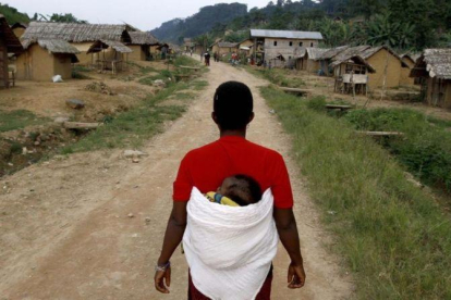 Una mujer congoleña se dirige caminano con su hijo en la espalda hacia la aldea de Luvungi.-AFP / MARC HOFFER