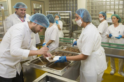 El chef Ricardo Temiño (en primer plano) coloca el lechazo en un plato ante la mirada del jefe de cocina del HUBU, Víctor Hernando y de un grupo de trabajadoras de la cocina del hospital.-ISRAEL L. MURILLO