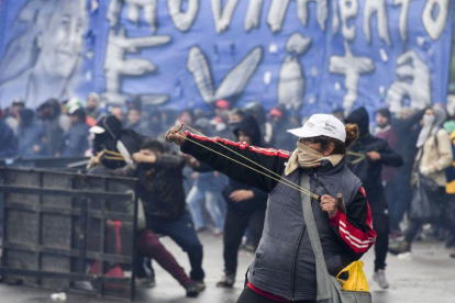 Un manifestante lanza una pieza durante las protestas en Buenos Aires por el ajuste económico aprobado por el Congreso.-AFP / EITAN ABRAMOVICH