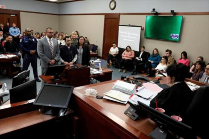 Larry Nassar, de pie, escucha la sentencia de la juez, ayer, en Michigan. Bajo esta foto algunas de sus víctimas.-/ REUTERS / MCDERMIN