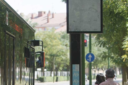 Dos personas caminan junto a un autobús municipal.-RAÚL G. OCHOA