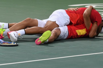 Rafa Nadal y Marc López se abrazan en el suelo tras clasificarse para la final olímpica.-AFP / LUIS ACOSTA