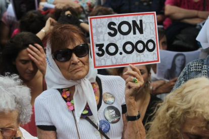 Una mujer sostiene un cartel en referencia a los 30.000 desaparecidos mientras escucha el veredicto por los crímenes cometidos en la ESMA, en Buenos Aires, el 29 de noviembre.-/ EFE / CARLOTA CIUDAD