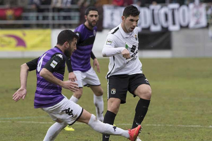 Carlos Ramos intenta el pase ante la presión de un jugador del Palencia.-JARCHA-BURGOSDEPORTE.COM