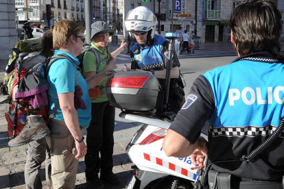 Dos agentes de la Policía Local resuelven las dudas de unos turistas en el centro de la ciudad.-ISRAEL L. MURILLO