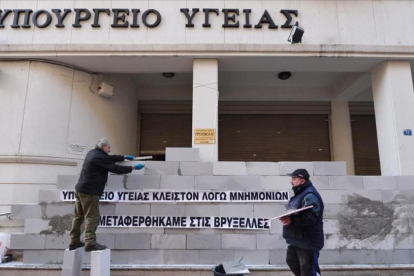 Manifestantes levantan un muro en la sede del Ministerio de Sanidad de Grecia con la inscripción 'Cerrado por el rescate. Hemos sido trasladados a Bruselas', en una protesta contra la austeridad en Atenas, en diciembre del 2016.-LOUISA GOULIAMAKI