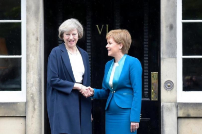 May (izquierda) y Sturgeon se dan la mano en la puerta de Bute House, en Edimburgo, este viernes.-AFP / LESLEY MARTIN