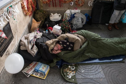 Un sintecho rodeado de motivos navideños que él mismo y un amigo colocaron en el exterior de la estación de metro de Green Park, el 16 de diciembre, en Londres.-/ GETTY IMAGES / CHRIS J. RATCLIFFE