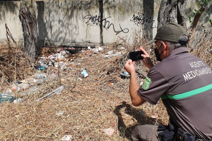 Un agente medioambiental documenta los daños en una zona de botellón pegada al parque Virgen Viñas. L. V.