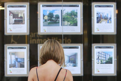 Una mujer observa anuncios de pisos en venta en el escaparate de una inmobiliaria. RAÚL G. OCHOA