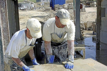 Dos operarios mueven placas de piedra en Villamayor-Ical