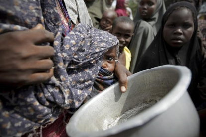 Una mujer con su bebé mientras hace cola para conseguir alimentos en un campamento para los desplazados de Mogadiscio (Somalia)-REUTERS