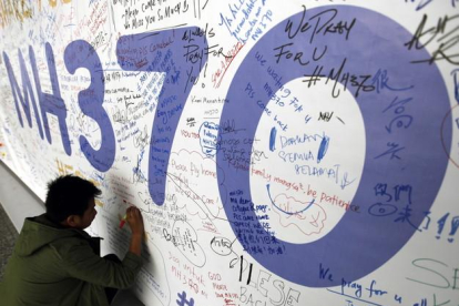 AUS01. KUALA LUMPUR (MALASIA), 30/07/2015.- Fotografía de archivo del 13 de marzo de 2014 de un hombre escribiendo mensajes en honor a las víctimas del vuelo MH370 de Malaysia Airlines en el aeropuerto internacional de Kuala Lumpur (Malasia).-EFE/MAK REMISSA